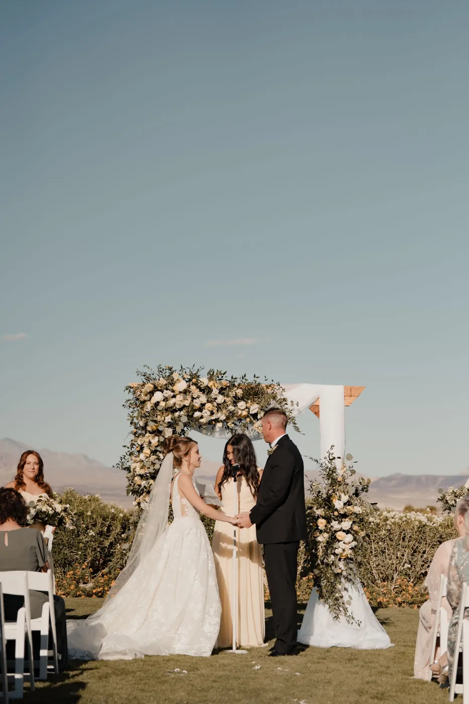Outdoor wedding ceremony under a floral arch